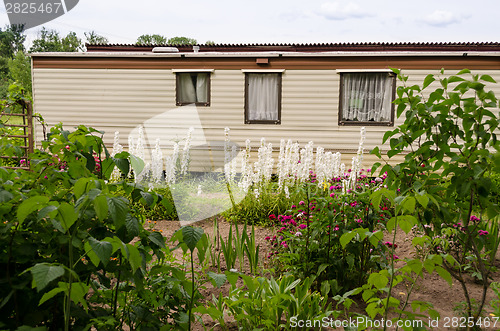 Image of travel mobile house in garden between the flowers  