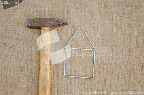 Image of old hammer and house made ??of nails linen texture 