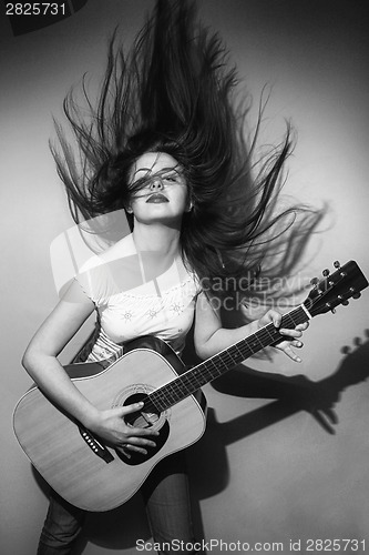 Image of Young woman wildly playing guitar black and white