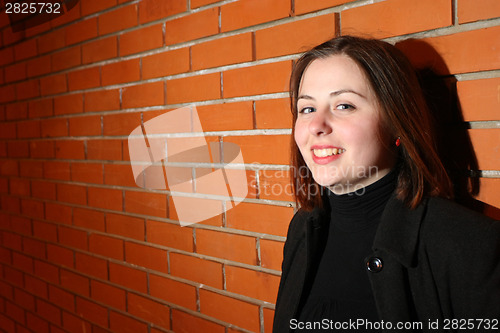 Image of Young brunette in front of brick wall