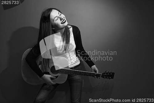 Image of Brunette enjoys playing guitar black and white