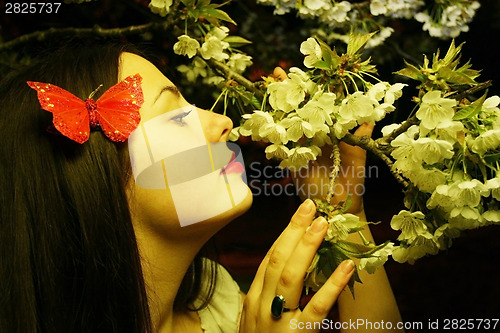 Image of Young woman posing with cherry blossom