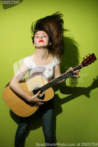 Image of Young brunette wildly playing guitar