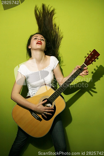 Image of Young woman passionately playing guitar