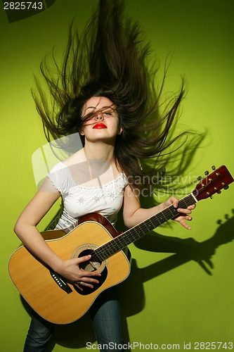 Image of Young woman wildly playing guitar