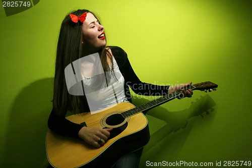 Image of Brunette playing guitar on green background