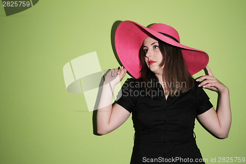 Image of Girl with pink straw hat on green background