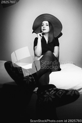 Image of Woman with pink straw hat on bed black and white