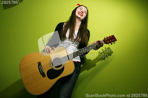 Image of Young brunette enjoys playing guitar