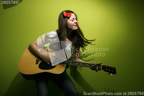 Image of Young woman enjoys playing guitar