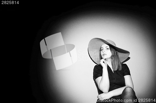 Image of Young woman with pink hat posing on bed black and white