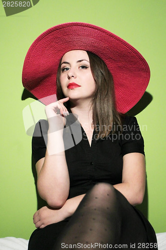 Image of Young woman with pink hat on bed