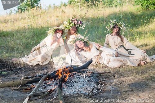 Image of Beautiful women with flower wreath near bonfire