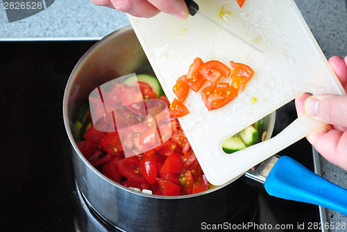 Image of Cutted tomatoes in a pot on the cooker  while frying