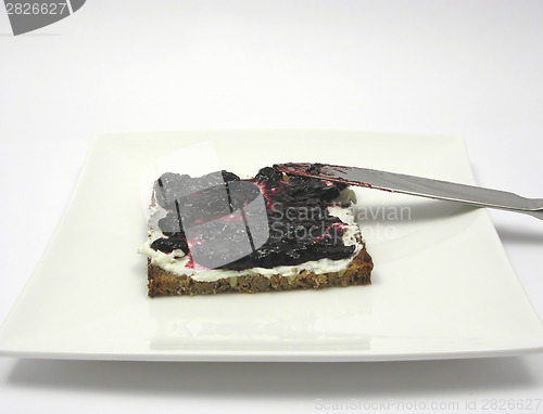 Image of Wholemeal bread with cream cheese and bilberry jam on a plate wi