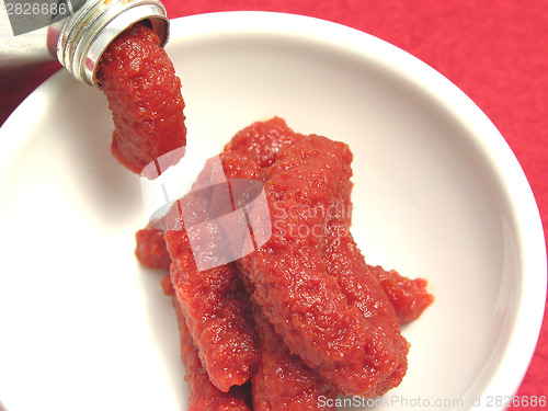 Image of Tomato puree pressed out of a tomato tube in a little bowl