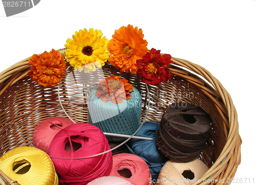 Image of A basketful of multi-coloured woolen yarn and flowers