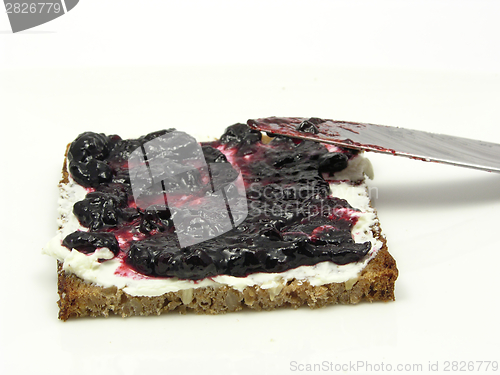 Image of Wholemeal butterbread  with bilberry jam placed on a round plate with knife