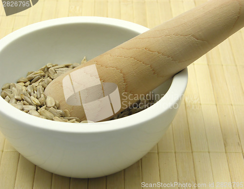 Image of Pestling sunflower seeds in a bowl of chinaware