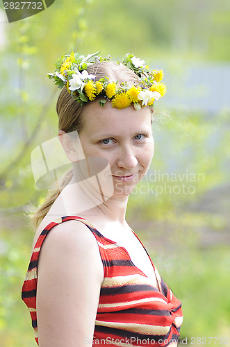Image of The happy woman with a wreath from yellow flowers on the head.
