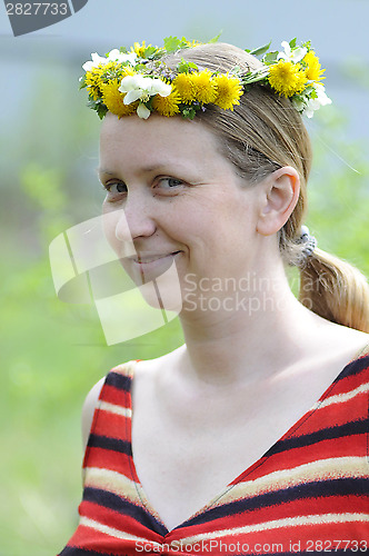 Image of The happy woman with a wreath from yellow flowers on the head.