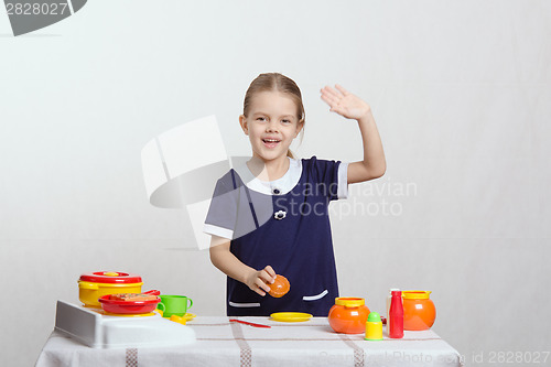 Image of Girl waving a toy kitchen