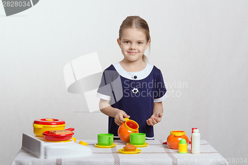 Image of Girl pours a cup of cream in children's kitchen