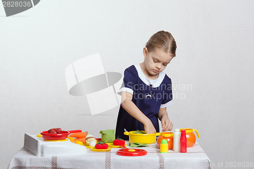 Image of Girl enthusiastically picks pan in the kitchen
