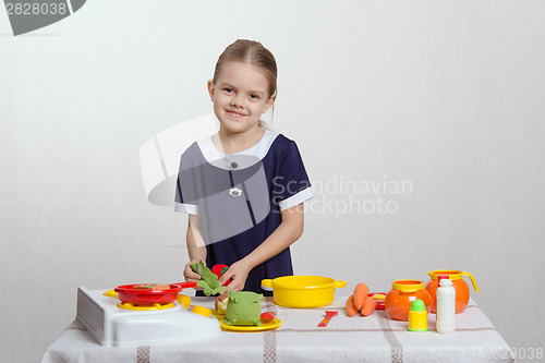 Image of Five year old girl puts cabbage leaf in pan