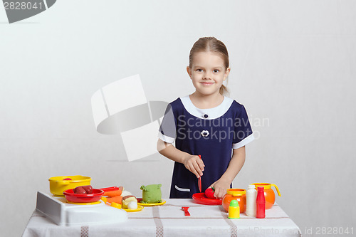 Image of girl having fun in the kitchen cutting tomato