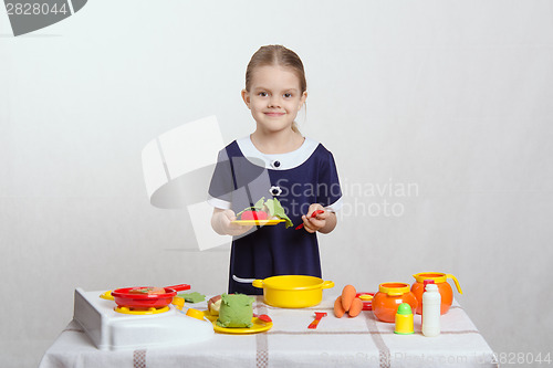 Image of Five-year hostess holds plate with a dish and spoon