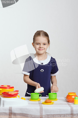 Image of Girl pouring milk a cup in the kitchen