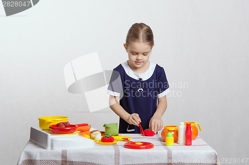 Image of Girl enthusiastically cuts tomato