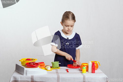 Image of Girl cuts a toy mushroom in the kitchen
