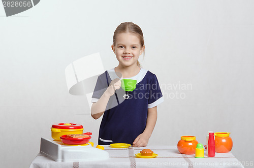 Image of Girl drinking from the cup at her kitchen