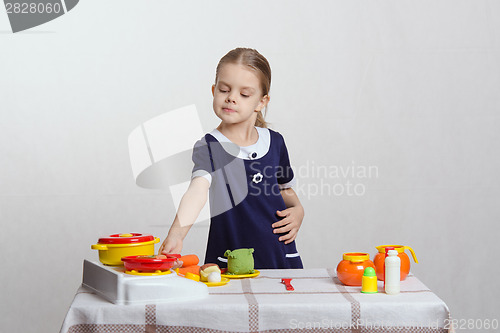 Image of Girl hostess putting the pan on stove