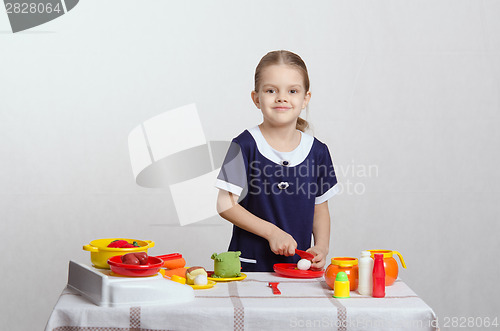 Image of Girl hostess cuts mushroom in the kitchen