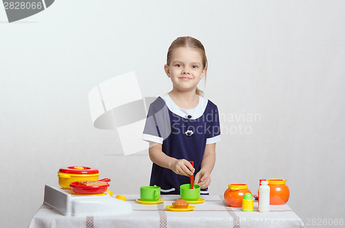 Image of Girl with a spoon in cup prevents children's kitchen