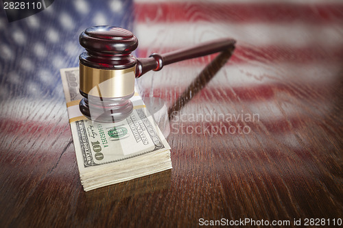 Image of Wooden Gavel Resting on Money with American Flag Reflection