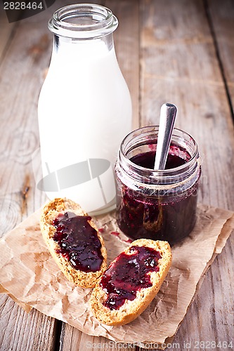 Image of black currant jam in glass jar, milk and crackers 