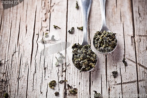 Image of two spoons of dried green tea leaves