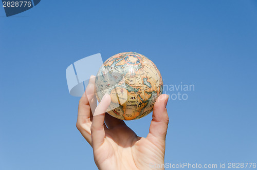 Image of global earth miniature in hand on sky background 