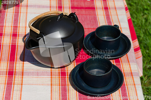 Image of black ceramic tea set on checked background 