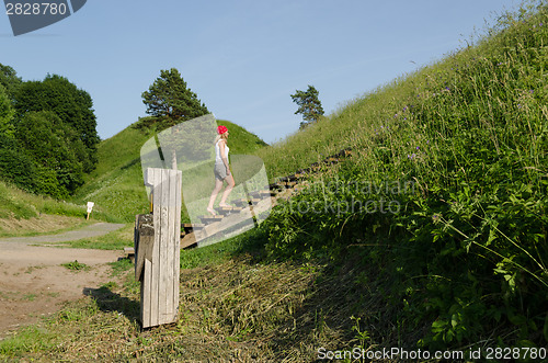 Image of tourist girl climb strairs on mound hill 