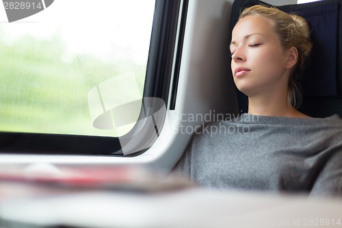 Image of Lady traveling napping on a train.