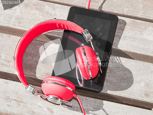 Image of Red colored headphones and tablet PC