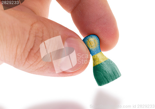 Image of Hand holding wooden pawn, flag painting, selective focus