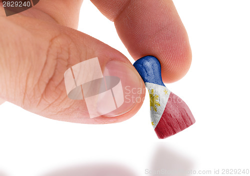 Image of Hand holding wooden pawn, flag painting, selective focus