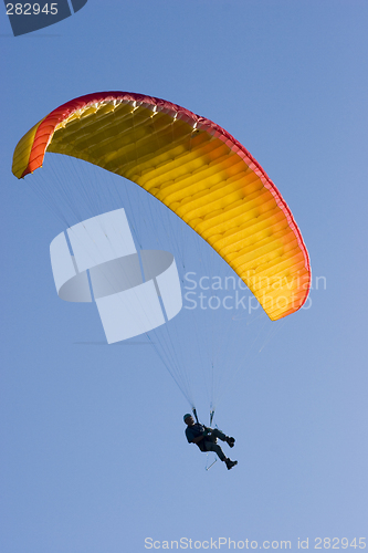 Image of Orange paraglider in a blue sky