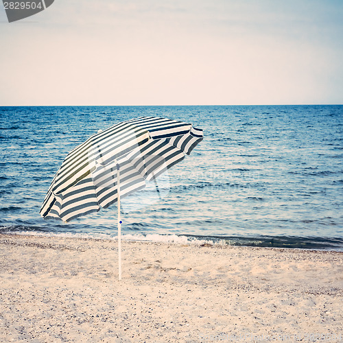 Image of Striped umbrella on sandy beach